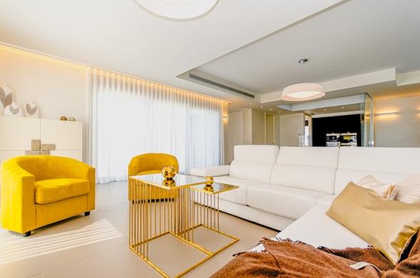 A bright, stylish living room in a modern short-term rental featuring neutral furniture, a yellow accent chair, and an open layout designed to appeal to vacation rental guests.