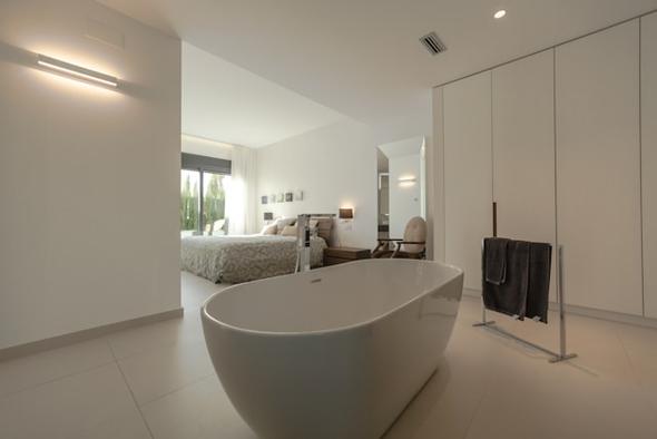 A modern luxury short-term rental bedroom featuring a freestanding bathtub, minimalist decor, and natural lighting, illustrating the type of high-value property often used as an STR investment.
