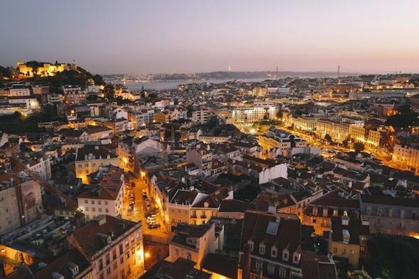 The historic center of Lisbon at dusk, a prime area for tourism. This image highlights the neighborhoods where operating a short-term rental is now heavily regulated due to new short-term rental restrictions designed to manage housing pressures.
